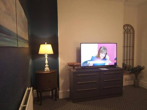 a flat screen tv sitting on a dresser with a lamp at Apartment One Aberystwyth Town Centre in Aberystwyth
