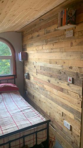 a bedroom with a wooden wall with a bed at Railway Pod, Castlewellan in Castlewellan