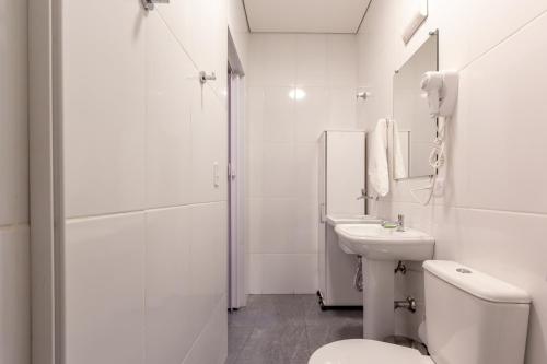 a white bathroom with a toilet and a sink at BH Studios Hotel Brás in Sao Paulo