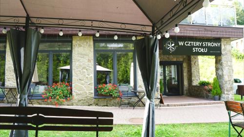 a tent in front of a building with a bench at Czarodziejska Góra Kozubnik Daglezja in Porąbka