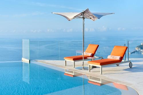 two chairs and an umbrella next to a swimming pool at The Maybourne Riviera in Roquebrune-Cap-Martin