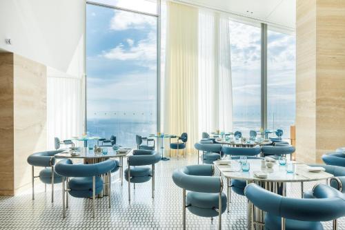 a restaurant with tables and chairs and large windows at The Maybourne Riviera, Maybourne in Roquebrune-Cap-Martin