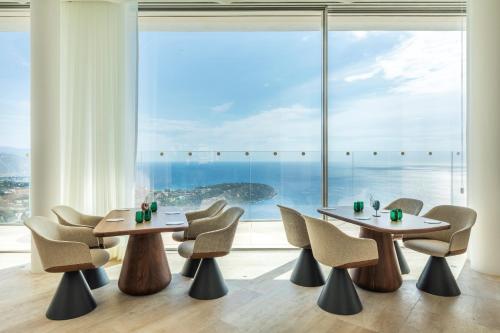 a dining room with tables and chairs and a large window at The Maybourne Riviera, Maybourne in Roquebrune-Cap-Martin
