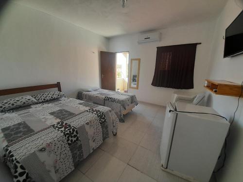 a room with two beds and a refrigerator in it at Pousada Progresso in Parnaíba