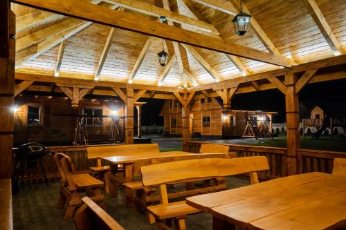 a wooden pavilion with wooden tables and wooden chairs at Domki przy Alei in Krasnobród