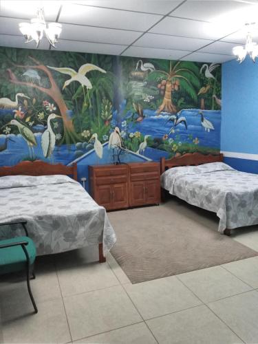 a room with two beds and a mural on the wall at Hospedaje Hefziba in Moyogalpa