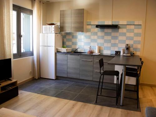 une petite cuisine avec une table et un réfrigérateur dans l'établissement Chez Léon - Clim' & Patio - Appart Loupian Centre, à Loupian