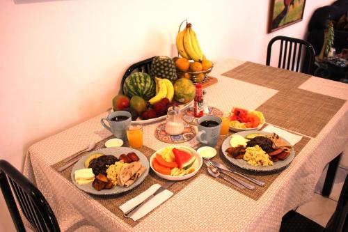 einen Tisch mit Teller mit Lebensmitteln und Obst darauf in der Unterkunft F&M Guesthouse in San José