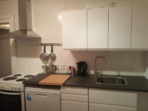 a kitchen with white cabinets and a sink and a stove at Apartment One Aberystwyth Town Centre in Aberystwyth