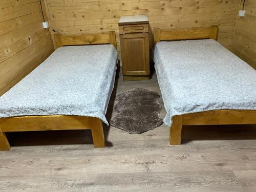 two twin beds in a room with a table at Brvnara Krin 1 in Nova Varoš
