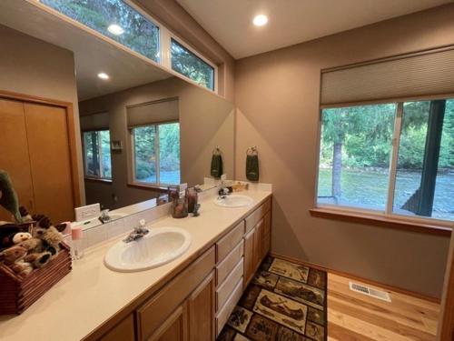 baño con 2 lavabos y espejo grande en Cozy Riverfront Retreat, en Leavenworth
