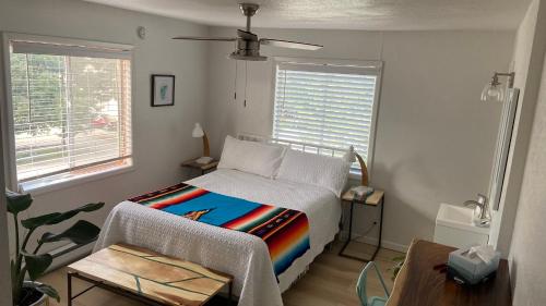 ein Schlafzimmer mit einem Bett, einem Tisch und zwei Fenstern in der Unterkunft The Summit Inn in Cloudcroft