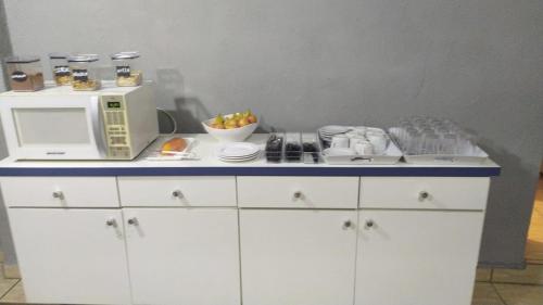 a kitchen with a microwave and a counter with dishes at Orquidário Praia Hotel in Santos