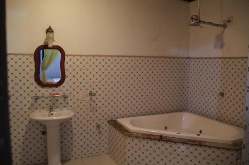 a bathroom with a sink and a tub and a mirror at Pousada La Maison du Baron in Alcântara