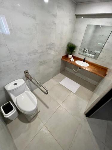 a white bathroom with a toilet and a sink at La Posada del Mar in Dominical