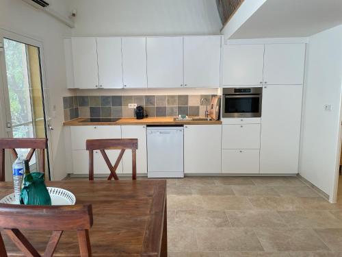 une cuisine avec des armoires blanches et une table en bois dans l'établissement Gîte l'Ouvèze, à Roaix