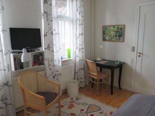 a bedroom with a table and chairs and a television at Foldenhus Ferieboliger og B&B in Bogense