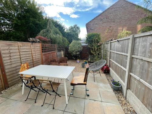 a patio with a table and chairs and a fence at Beautiful Town House with Private Garden and Patio in Canford Magna