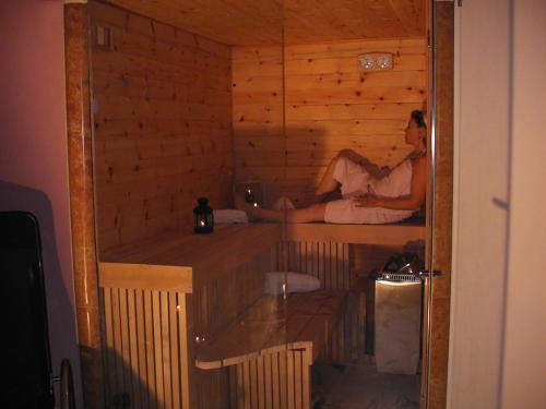 a woman is sitting in a sauna at B&B Al Cristo in SantʼAmbrogio di Valpolicella