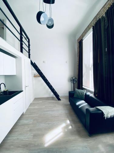 un soggiorno con un divano nero e una scala di B&W Apartment a Riga