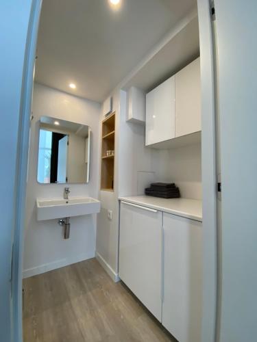 una cucina bianca con un lavandino e uno specchio di B&W Apartment a Riga