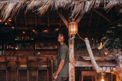 un homme tenant une lumière sur un poteau dans une barre dans l'établissement Lost Paradise Gili, à Gili Trawangan