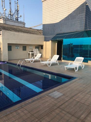 a patio with chairs and a pool on top of a building at Palladium Apart Service in São Vicente