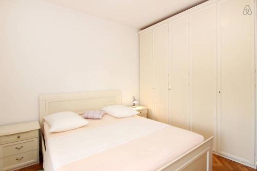 een witte slaapkamer met een bed en een ladekast bij Apartment Happy Day in Split