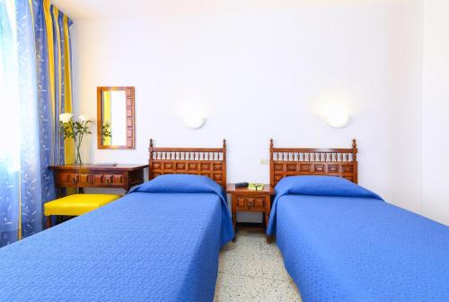 1 dormitorio con 2 camas, escritorio y espejo en Caroni, en Playa del Inglés