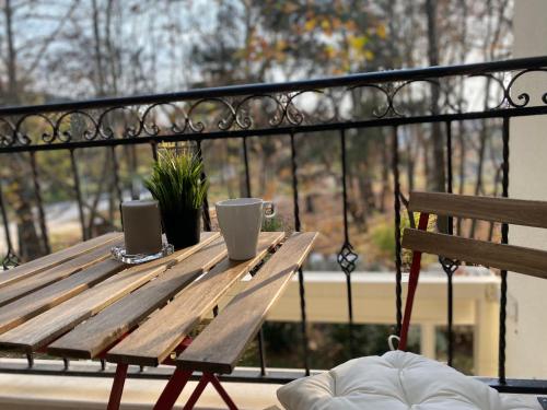 a wooden table with two cups and a bench on a balcony at Green park Sandanski in Sandanski