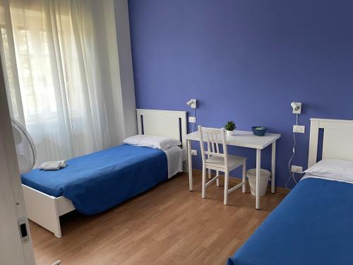 a room with two beds and a table and a blue wall at Villa Vittoria in Stresa