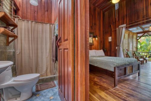 a bathroom with a bed and a toilet in a room at Hotel Banana Azul - Adults Only in Puerto Viejo