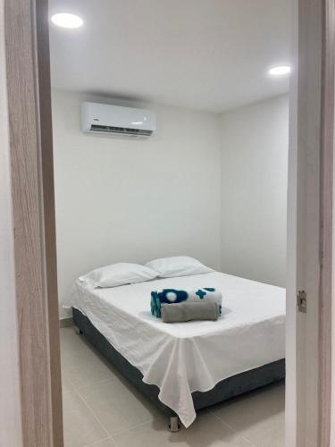 1 dormitorio con 1 cama con sábanas blancas y toallas azules en Casa Sonia en Cartagena de Indias