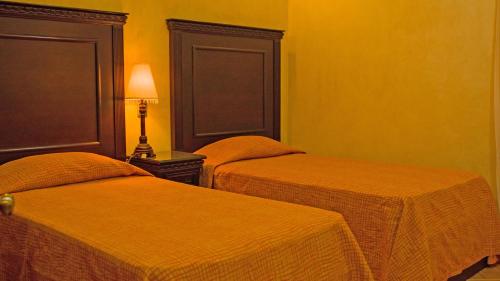 Duas camas num quarto com paredes amarelas em Suites Bello Xochimilco by DOT Tradition em Oaxaca de Juárez
