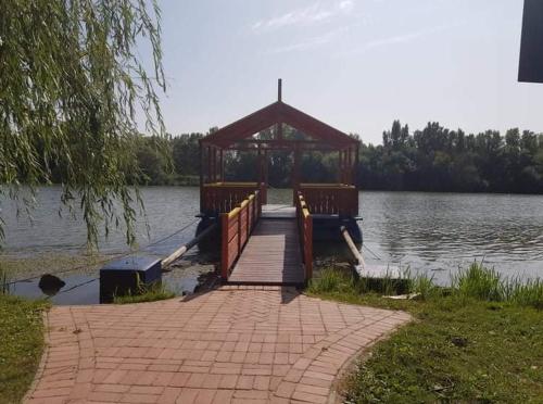a wooden dock with a gazebo on a lake at ZöldPortál Vendégház Tiszanána -Dinnyéshát 