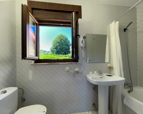 baño con lavabo y aseo y ventana en Hotel Rural "La Ruta De Cabrales", en Mestas de Con