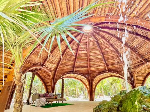 a room with a large wooden ceiling with a palm tree at Ku kuk Glamping in Chemuyil