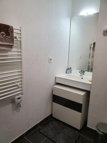 La salle de bains blanche est pourvue d'un lavabo et d'un miroir. dans l'établissement GK2night, à Marseille