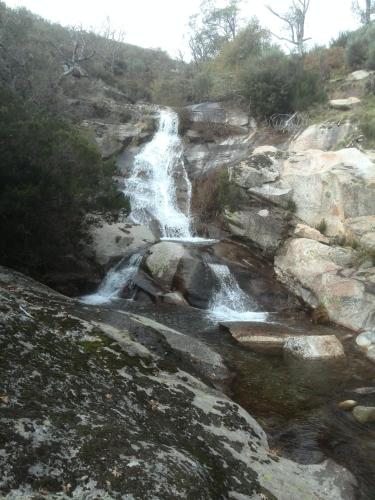 a waterfall on the side of a rocky mountain at Hostal Yuste in Garganta la Olla