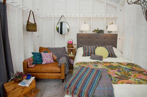 ein Schlafzimmer mit einem Bett, einem Sofa und einem Stuhl in der Unterkunft Laggan Bothies in Spean Bridge