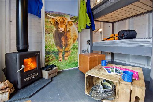 a room with a stove and a cow on the wall at Laggan Bothies in Spean Bridge