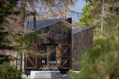 a wooden house with two chairs in front of it at Laggan Bothies in Spean Bridge