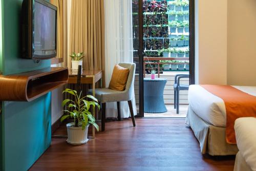 a hotel room with a bed and a tv and a balcony at Giraffe Boutique Hotel in Baguio