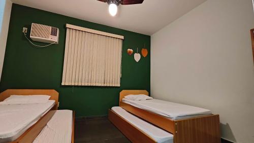een kamer met 2 bedden en een groene muur bij Casinha de Boneca em Juquey in Juquei