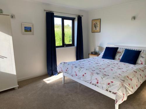 um quarto com uma cama com almofadas azuis e uma janela em Ty Aelwyd em St. Davids