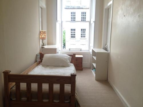 a bedroom with a bed and a large window at Beautiful Georgian New Town Flat in Edinburgh