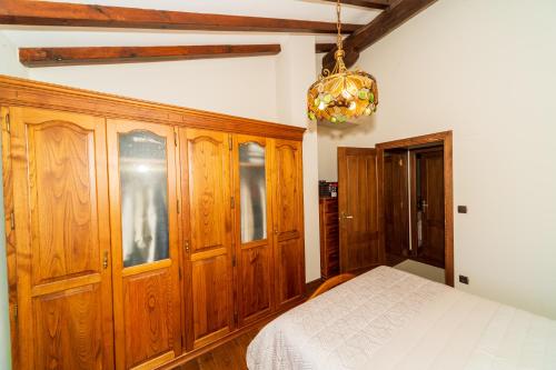 a bedroom with a bed and wooden cabinets and a chandelier at VILLA DOLARETXE by Urdaibai Rentals in Bilbao