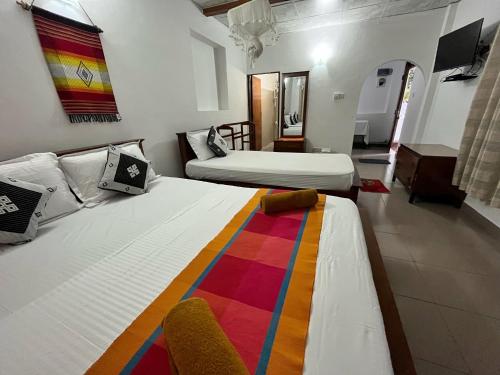 a hotel room with two beds and a colorful blanket at Crystal Lake Resort in Kandy