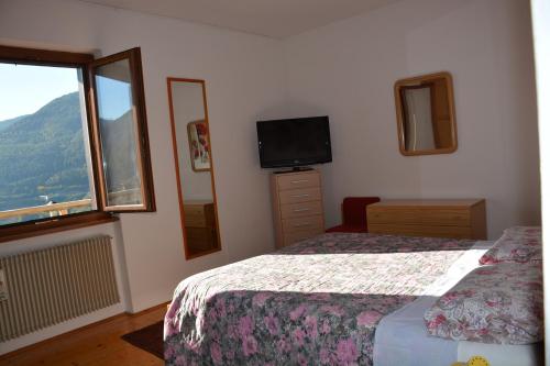 a bedroom with a bed and a tv and a window at Apt. BELLA VISTA nel Cuore della Valle di Cembra. in Segonzano