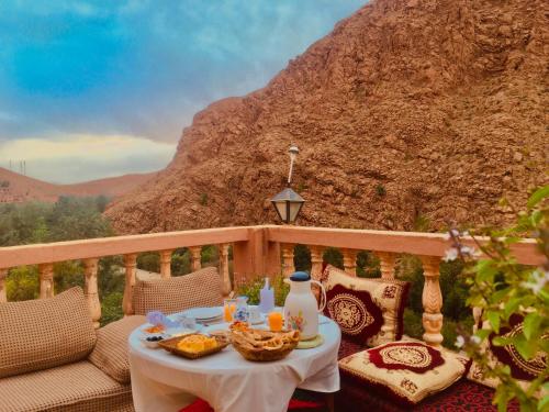 una mesa con comida en un balcón con una montaña en Hôtel panoramique de la vallée en Aït Idaïr